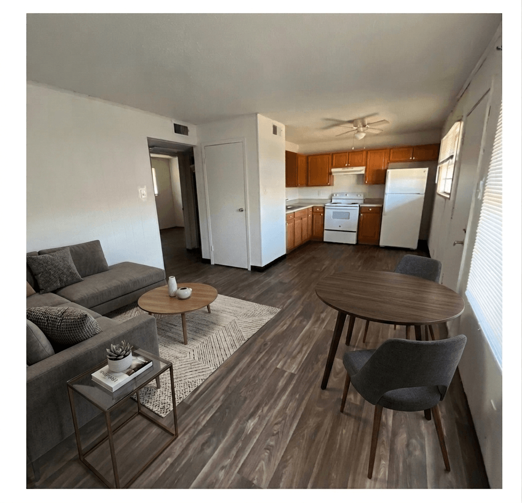 A living room with a grey couch, a coffee table, and a dining table.